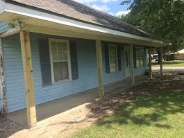 A blue house with a porch and shutters on it.