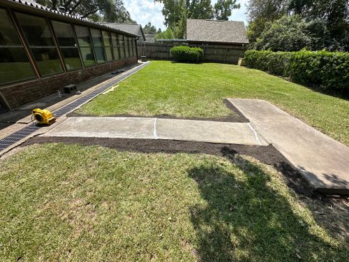 A concrete walkway is being built in the backyard of a house.