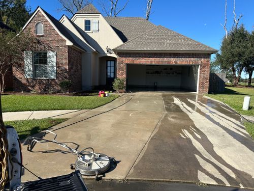 A brick house with a driveway being cleaned by a machine.