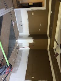 A room with brown walls and white trim is being painted.