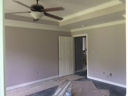 An empty room with a ceiling fan and a door.