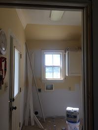 A room with a window and a bucket of paint in it.