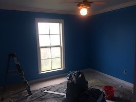 An empty room with blue walls and a window.