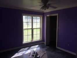 A room with purple walls and a ceiling fan.