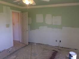 A room with green walls and a ceiling fan is being painted.