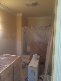 A bathroom is being painted and covered in plastic.