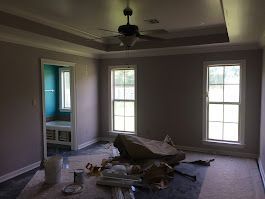 An empty room with a ceiling fan and three windows.