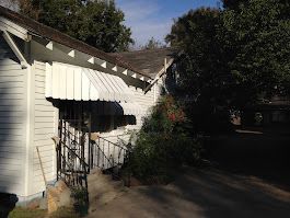 A white house with a white awning on the front of it.