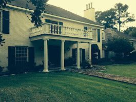A large white house with a large porch and a balcony.