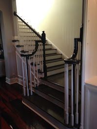 A staircase with white railings and black steps in a house.
