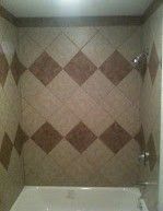A bathroom with a tub and a shower with a checkered tile wall.