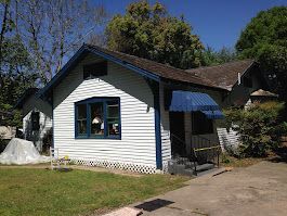 A small white house with a blue awning on the front porch.
