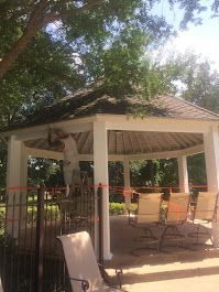 A man is painting the roof of a gazebo.