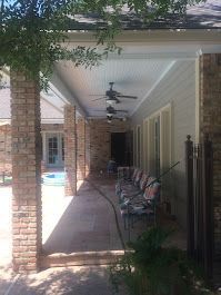 A large covered porch with a ceiling fan and chairs.