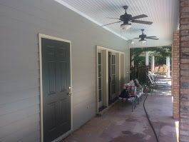 There is a ceiling fan on the porch of a house.