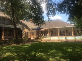 A large house with a swimming pool in the backyard surrounded by trees.