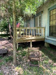 A wooden deck with a chair on it in front of a house.