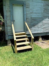 A set of wooden stairs leading up to a door on the side of a house.