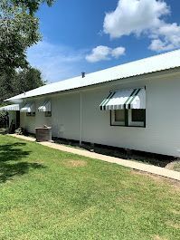 A white house with green and white awnings on the windows.