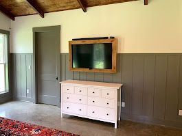 A living room with a dresser and a flat screen tv mounted to the wall.