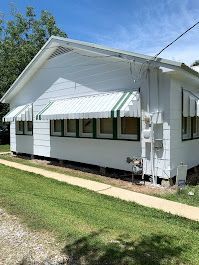 A white house with a green awning on the side of it.