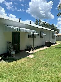 A white house with a green door and a white awning on the side of it.