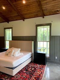 There is a bed in the middle of the room with a rug on the floor.