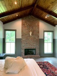 A bedroom with a brick fireplace and a deer skull on the wall.