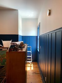 A hallway with blue paneling and a wooden floor.