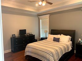 A bedroom with a bed, dresser, nightstand, television,and ceiling fan.