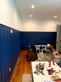 A room with blue walls, wooden floors, a table and chairs.