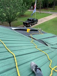 A person is laying on a green roof with a yellow rope.