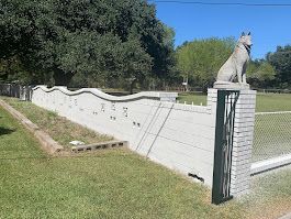 A statue of a wolf is sitting on top of a brick wall.