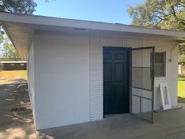A white shed with a black door and screen door.