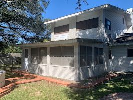 A white house with a screened in porch in the backyard.