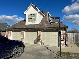 A car is parked in front of a house with a basketball hoop.