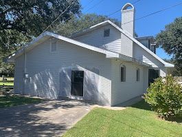 A white house with a chimney on the side of it is for sale.