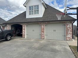 A truck is parked in front of a garage with a basketball hoop on the roof.