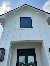 The front of a white house with a black door and a window.