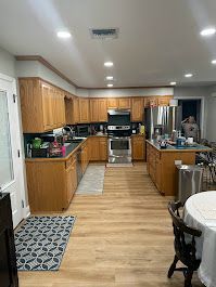 A kitchen with wooden cabinets , stainless steel appliances , a table and chairs.