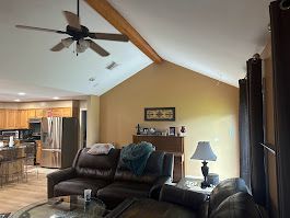 A living room with a couch , chair , table and ceiling fan.
