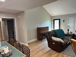 A living room with a couch , chair , table and piano.