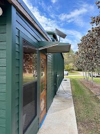 A green building with a wooden door and a walkway leading to it.