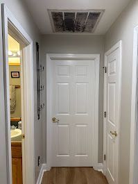 A hallway with white doors leading to a bathroom and a sink.