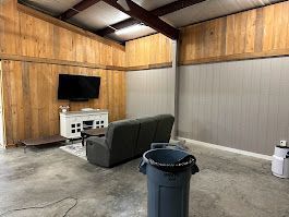 A living room with a couch , television , and trash can.