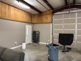 A living room with a couch and a trash can in a garage.
