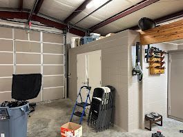 A garage with a ladder and chairs in it.