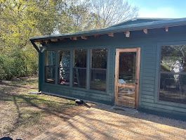 A green house with a lot of windows and a door.