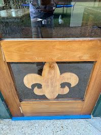 A wooden door with a fleur de lis carved into it.