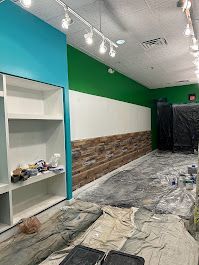 A room with green walls and white shelves is being painted.